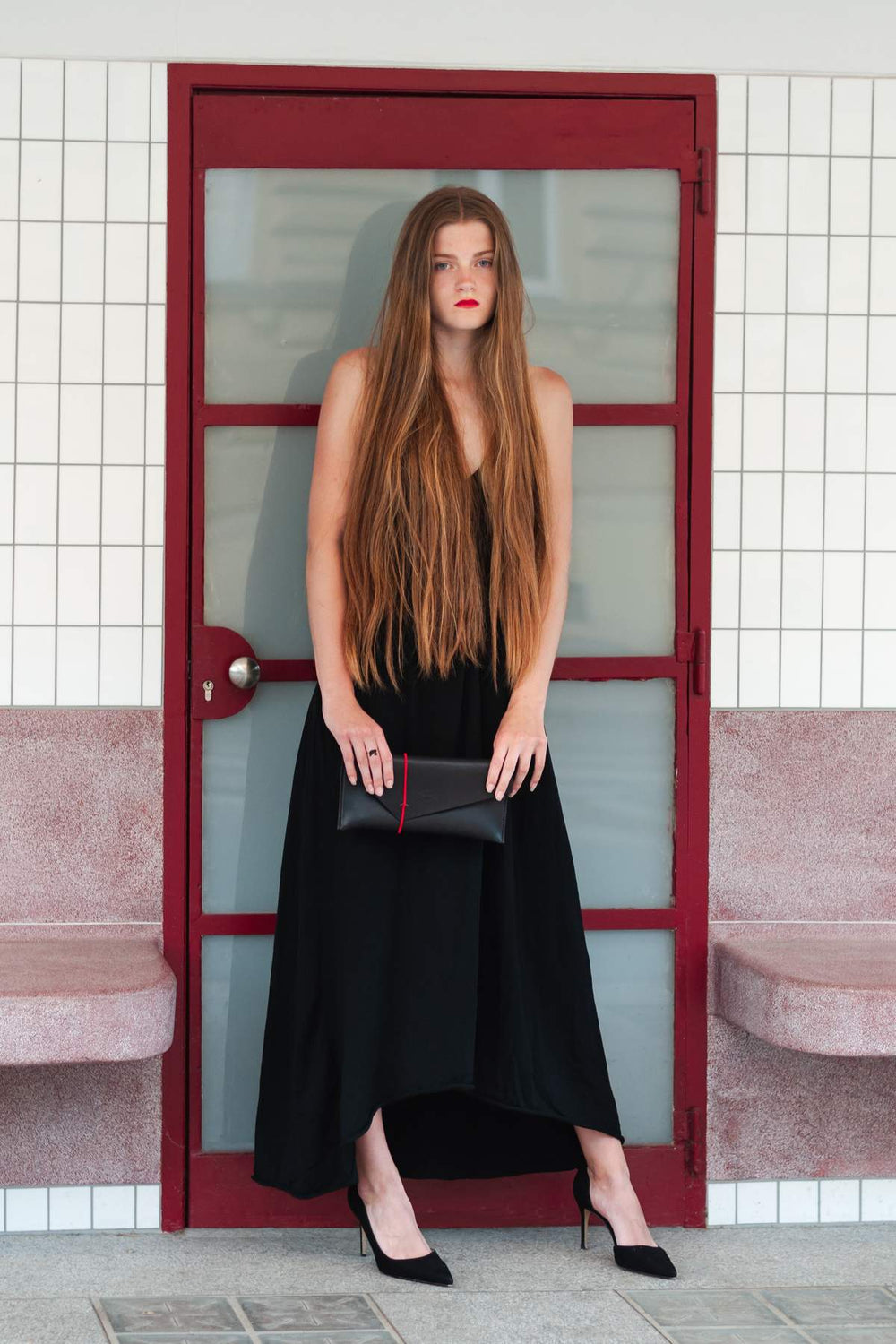 Woman holding a black clutch  with red strap