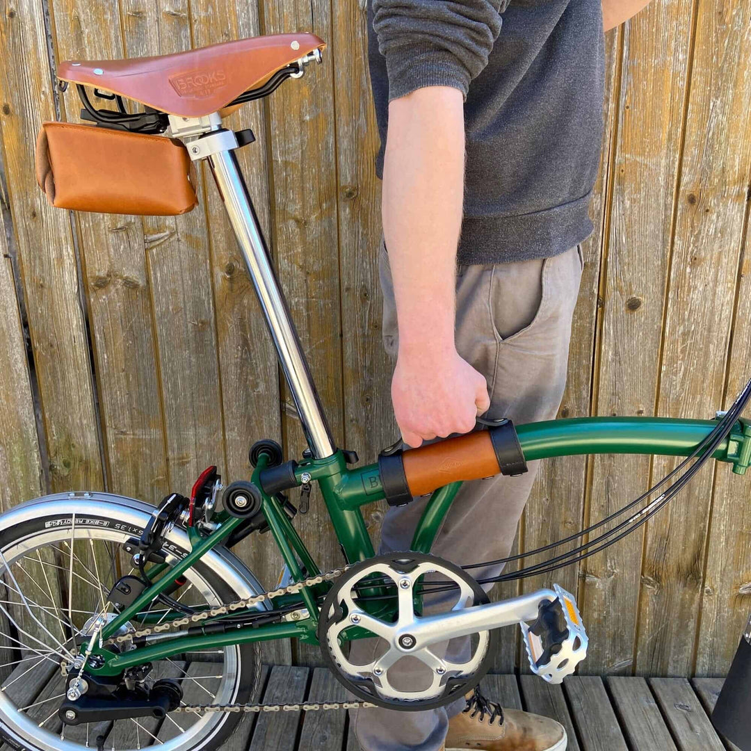 Honey and black Leather Brompton Carry Handle - Brompton accessories - person holding the bike