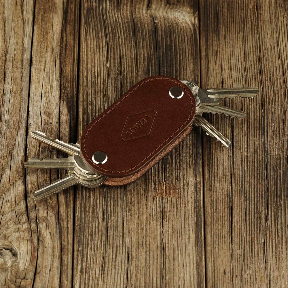 Brown leather key organizer with multiple keys on a wooden surface