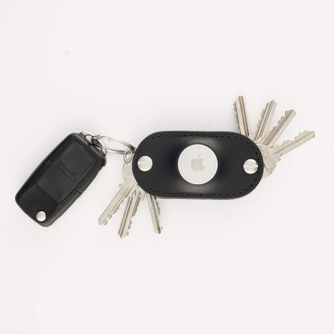 Black leather AirTag key organizer on a white background with car key