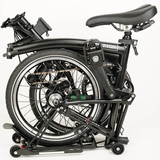 Folded Brompton bike with green leather chain and hook protector