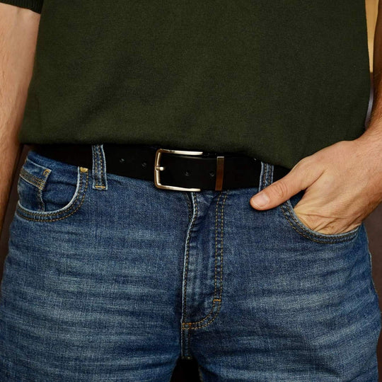 Person wearing a black belt with a shiny buckle on blue jeans.