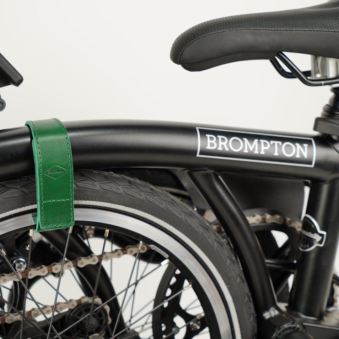 Leather Brompton Wheel Frame strap and Trouser Strap, pants strap, green colour on folded black Brompton bike, in use