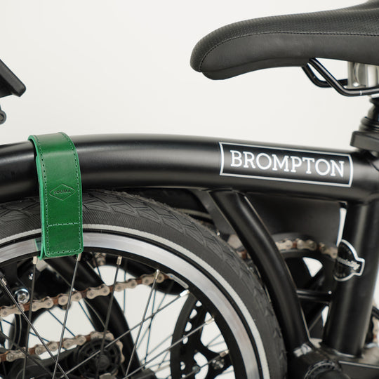 Leather Brompton Wheel Frame strap and Trouser Strap, pants strap, green colour on folded black Brompton bike, in use