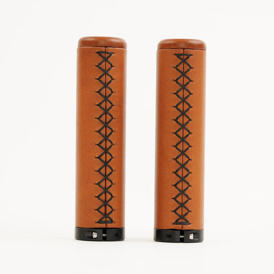 Two honey leather grips with black stitching on a white background