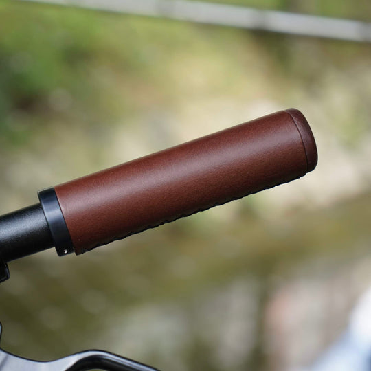 Close-up of a brown bicycle handlebar grip with a blurred natural background