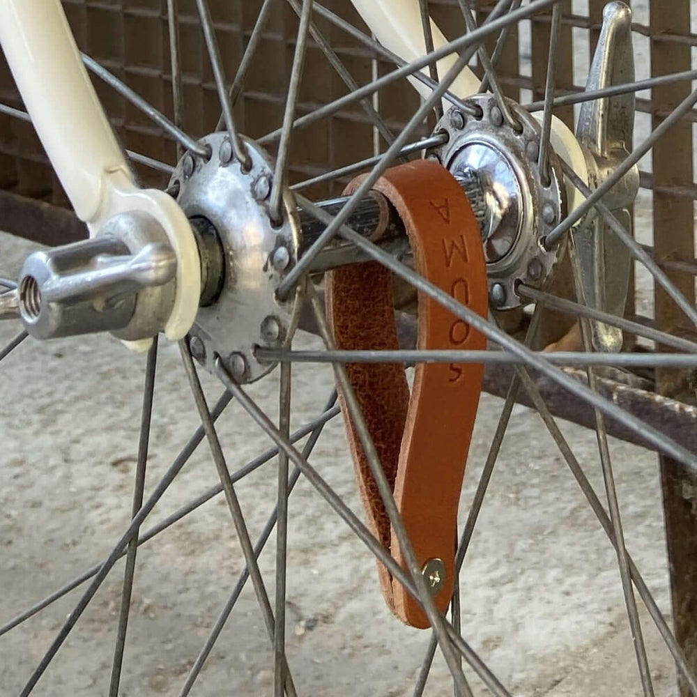 Close-up of a bicycle hub with a honey leather strap attached