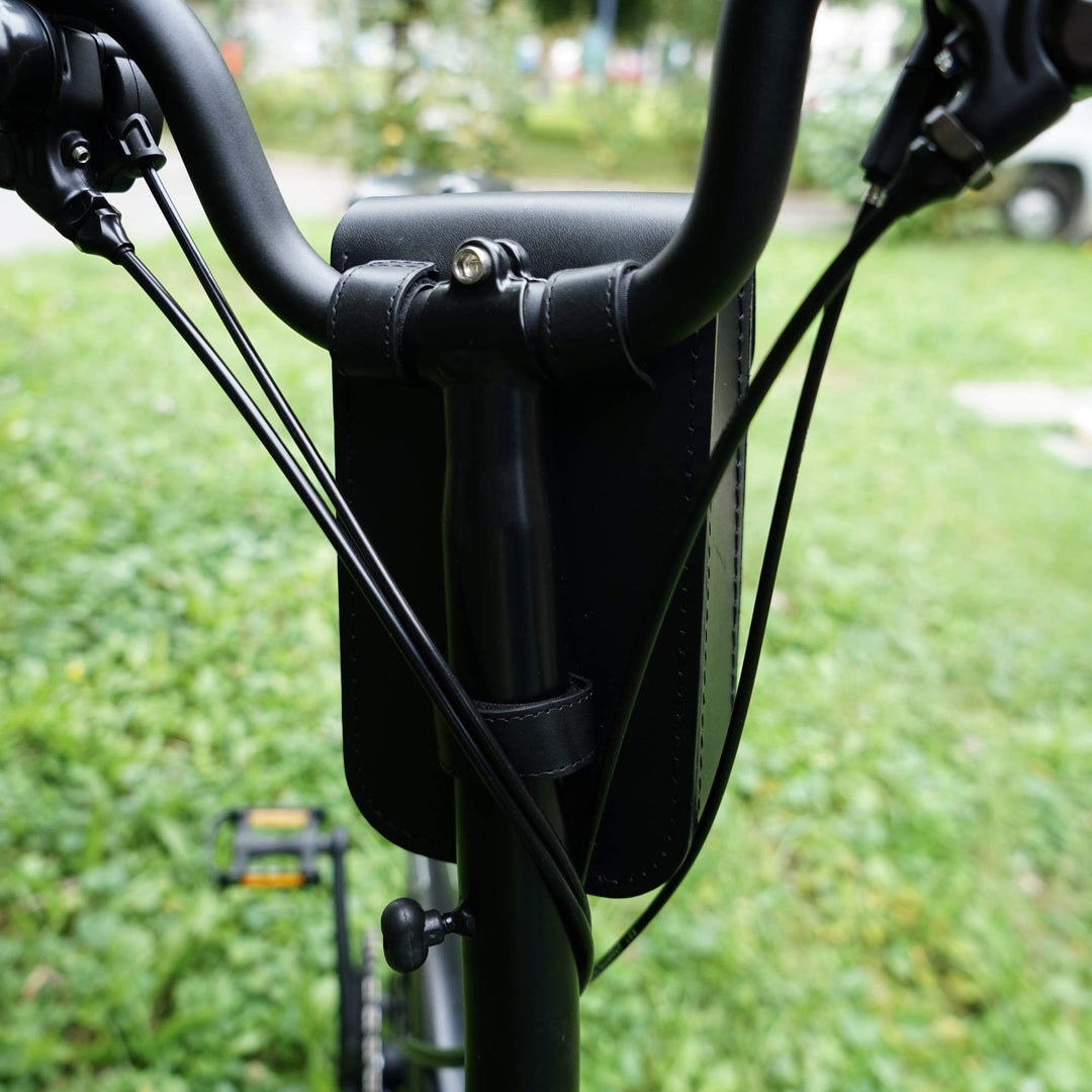 Close-up of a black bicycle handlebar bag straps, blurred green background