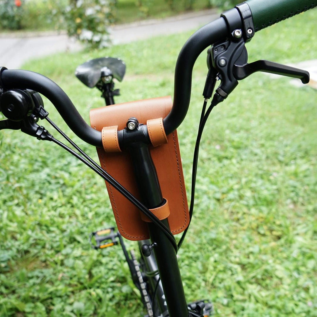 Honey leather bicycle handlebar bag  attached to bike handlebars with green grass background