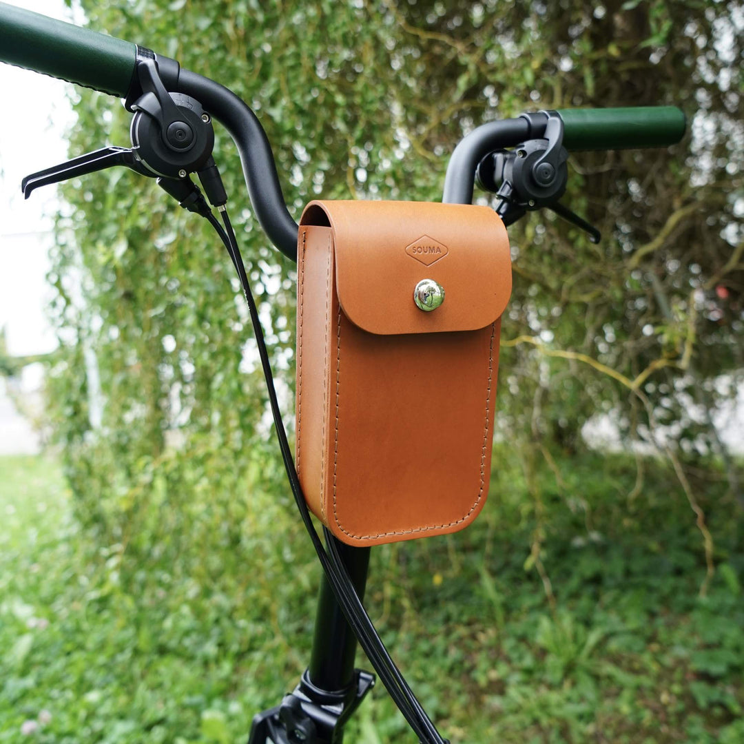 Honey leather bike handlebar bag with a blurred green background