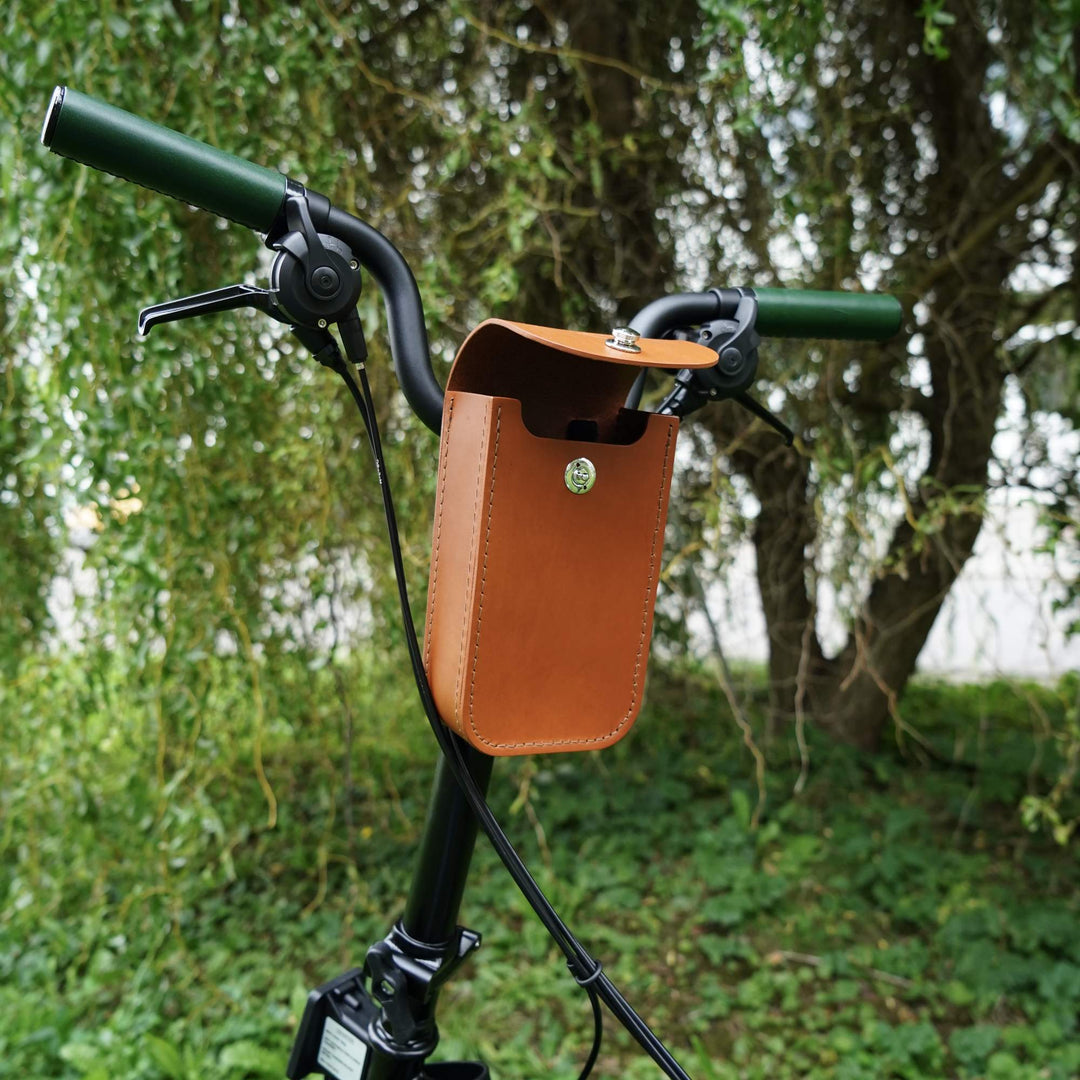 Honey leather bicycle handlebar bag  open with green trees in the background