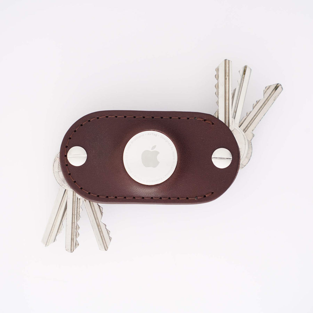 Brown leather airtag key organizer with multiple keys on a white background