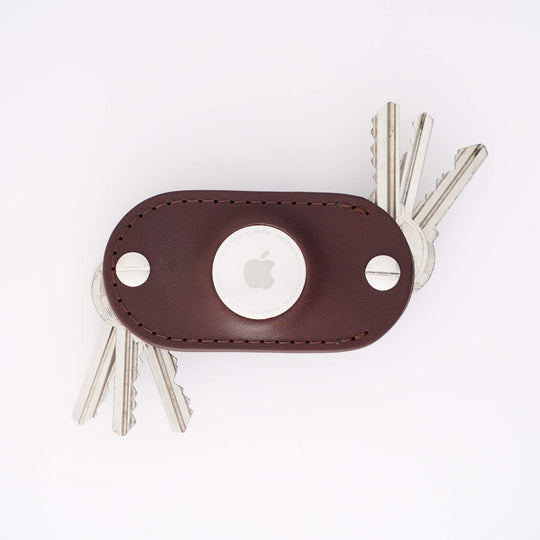 Brown leather airtag key organizer with multiple keys on a white background