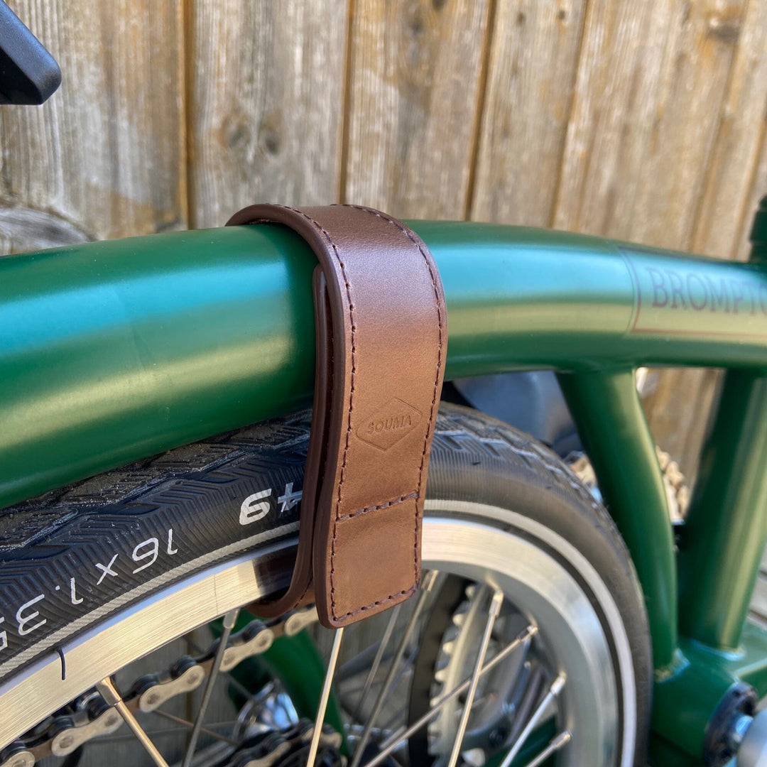 Brown version of Brompton leather wheel frame strap and trousers strap 2in1 side view with Brompton bicycle